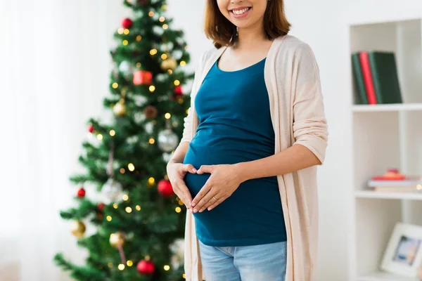 クリスマスに心で妊娠中の女性のクローズ アップ — ストック写真