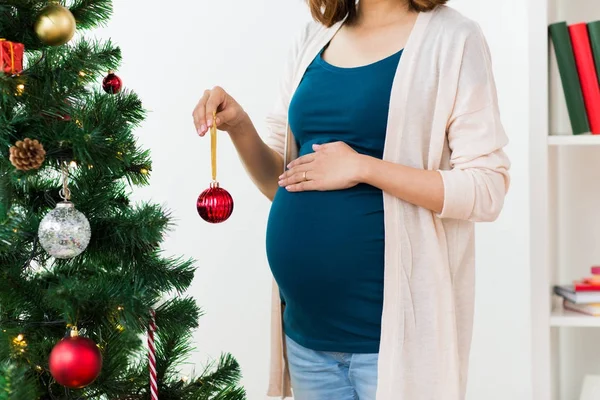 Mujer embarazada decorando árbol de Navidad — Foto de Stock