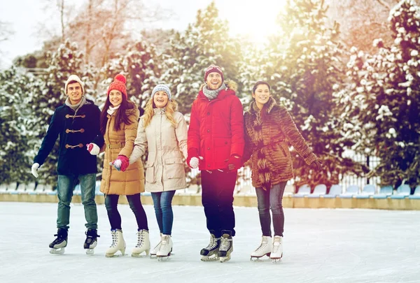 Amigos felices patinaje sobre hielo en pista al aire libre —  Fotos de Stock