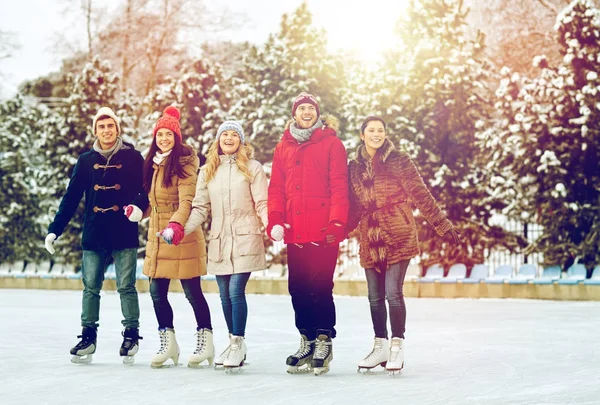 Happy friends ice skating on rink outdoors — Stock Photo, Image