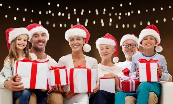 Happy family in santa hats with christmas gifts — Stock Photo, Image