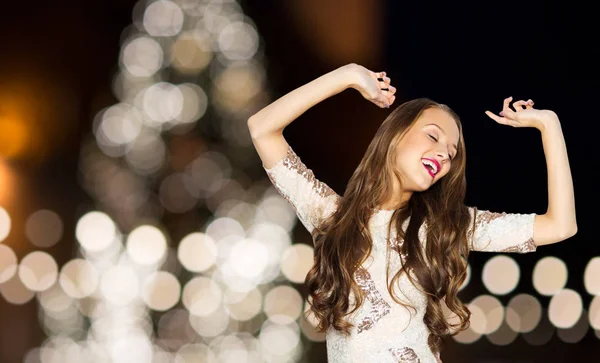 Happy young woman over christmas tree lights — Stock Photo, Image