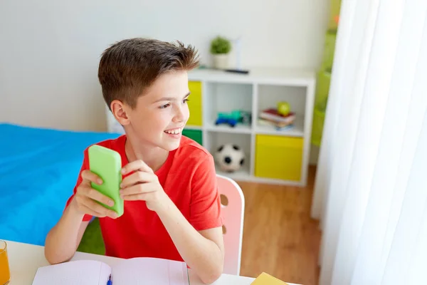 Estudante menino com smartphone distraindo de estudo — Fotografia de Stock