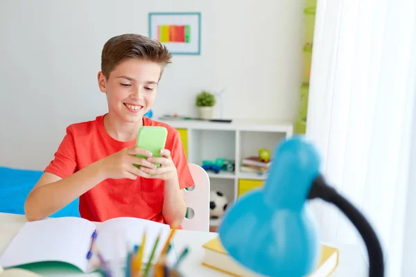 Estudante menino com smartphone distraindo de estudo — Fotografia de Stock