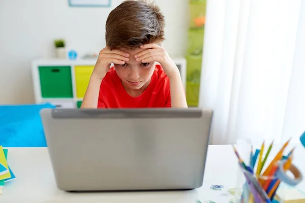Menino estudante cansado com computador portátil em casa — Fotografia de Stock