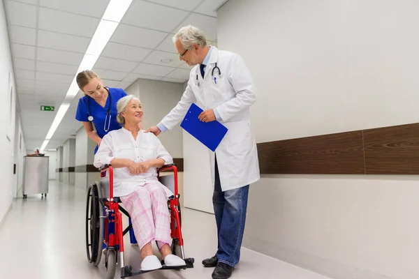 Médicos y pacientes mayores en silla de ruedas en la clínica —  Fotos de Stock