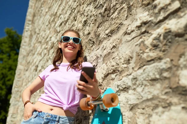 Happy teenage girl with longboard and smartphone — Stock Photo, Image