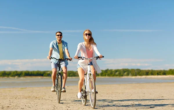 海辺で自転車に乗って幸せな若いカップル — ストック写真