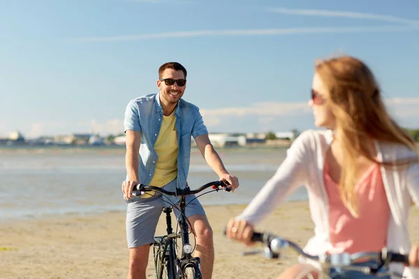 Счастливая молодая пара на велосипедах на берегу моря — стоковое фото