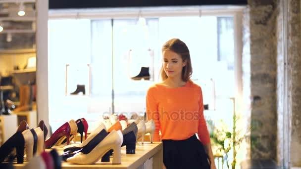 Счастливая молодая женщина выбирает обувь в магазине — стоковое видео