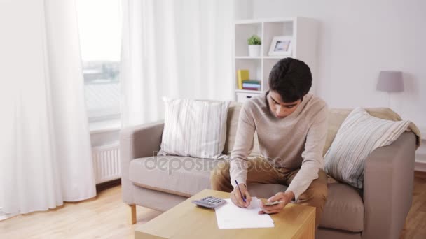 Homme avec calculatrice comptant l'argent à la maison — Video