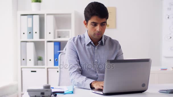 Hombre de negocios con portátil llamando por teléfono en la oficina — Vídeos de Stock