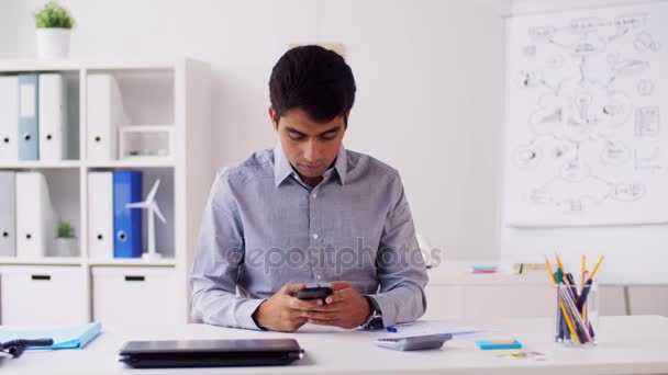 Бизнесмен со смартфоном и бумагами в офисе — стоковое видео