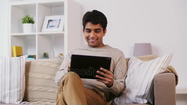 Man with tablet pc sitting on sofa at home — Stock Video