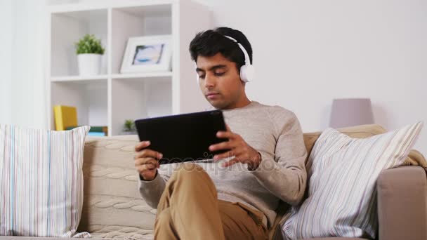 Hombre con tablet PC y auriculares en casa — Vídeo de stock