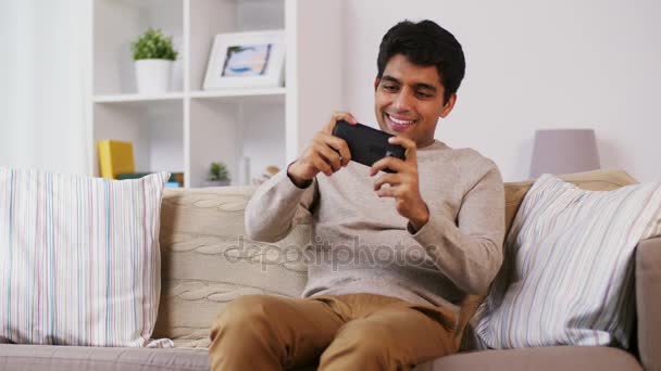 Man playing game on smartphone at home — Stock Video