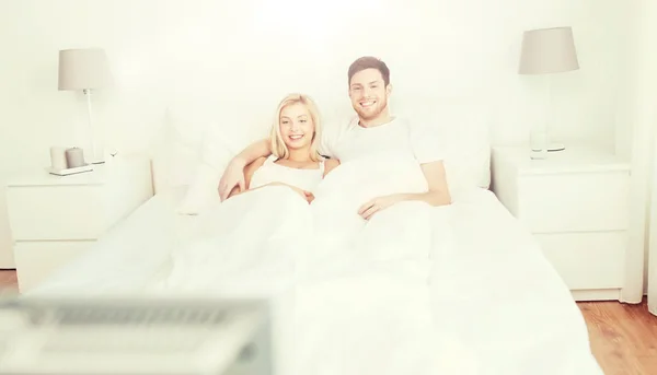 Heureux couple couché dans le lit à la maison et regarder la télévision — Photo