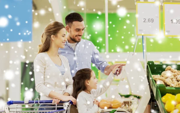 Familie met een gewicht van sinaasappelen op schaal in supermarkt — Stockfoto