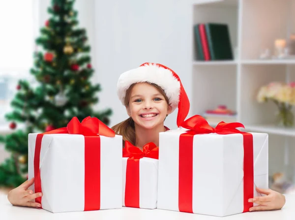 Улыбающаяся девушка в шляпе Санты с рождественскими подарками — стоковое фото