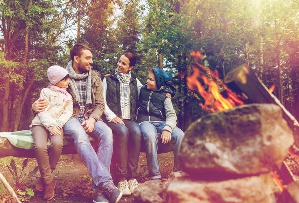 Happy family sitting on bench at camp fire — Stock Photo, Image