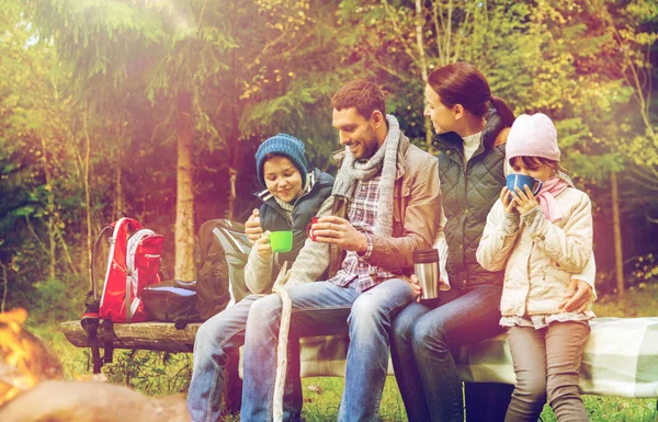 Happy family sitting on bench at camp fire — Stock Photo, Image