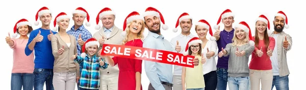 People in santa hats with sale sign at christmas — Stock Photo, Image