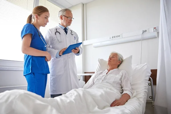 Médico y enfermera visitando a una mujer mayor en el hospital — Foto de Stock