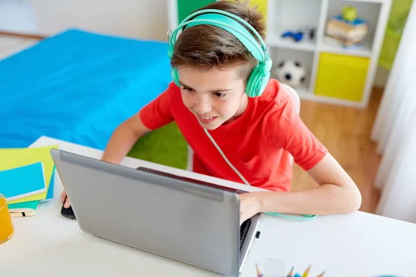 Мальчик в наушниках играет в видеоигры на ноутбуке — стоковое фото