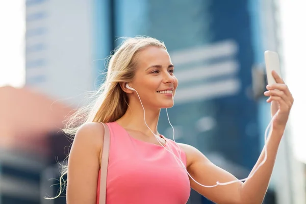 Gelukkig jonge vrouw met smartphone en koptelefoon — Stockfoto