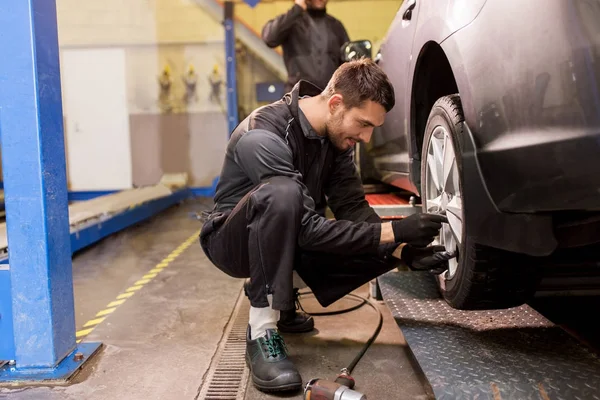 Mecânico automático com chave de fenda trocando pneu do carro — Fotografia de Stock