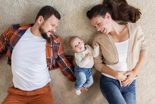 Familia feliz con el bebé acostado en el suelo en casa —  Fotos de Stock