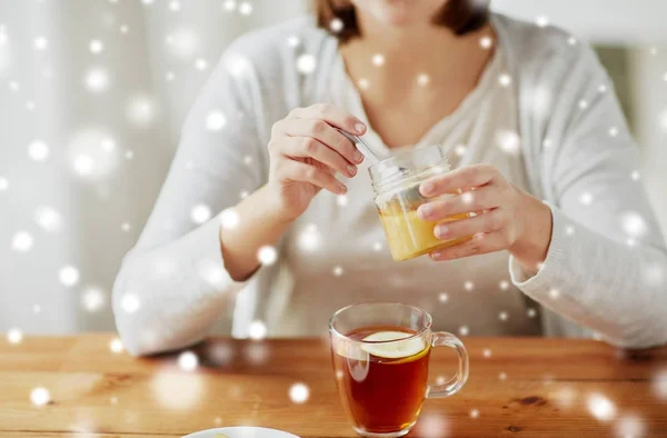 Nahaufnahme einer Frau, die dem Tee mit Zitrone Honig hinzufügt — Stockfoto