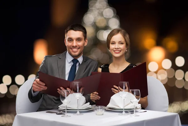Улыбающаяся пара с меню в рождественском ресторане — стоковое фото