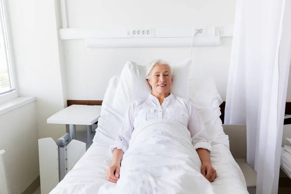 Sorrindo mulher idosa deitada na cama na enfermaria do hospital — Fotografia de Stock