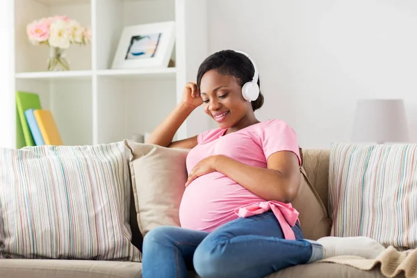Kobieta w ciąży w słuchawkach w domu — Zdjęcie stockowe