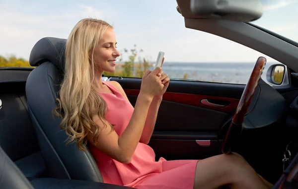 コンバーチブル車でスマート フォンを持つ若い女性 — ストック写真