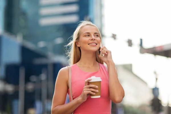 Kvinna med kaffe uppmanar smartphone i city — Stockfoto