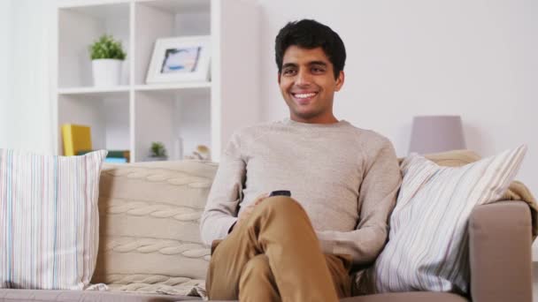 Man with remote control watching tv at home — Stock Video