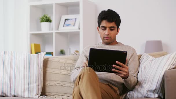 Man with tablet pc sitting on sofa at home — Stock Video