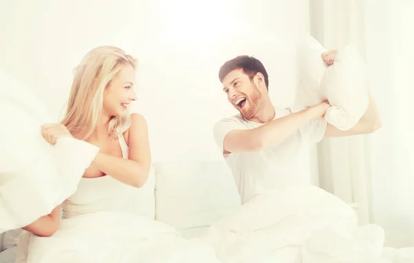 Feliz pareja teniendo almohada lucha en cama en casa — Foto de Stock