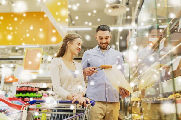 Gelukkige paar met winkelwagentje in supermarkt — Stockfoto