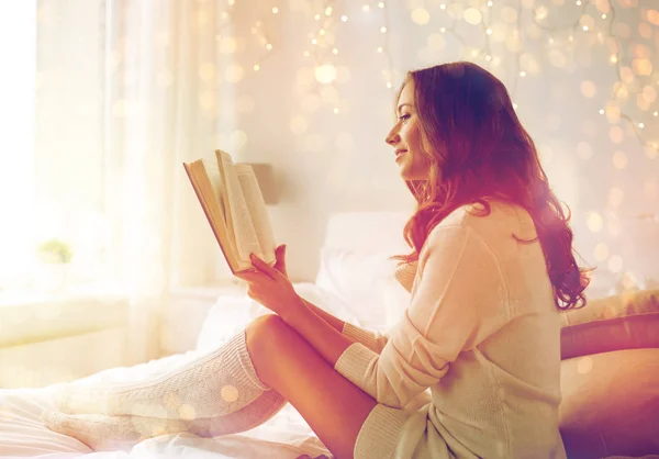 Jovem feliz lendo livro na cama em casa — Fotografia de Stock