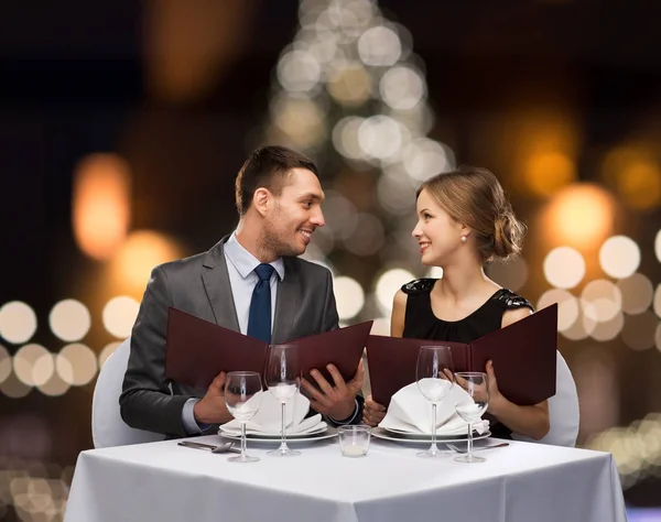 Smiling couple with menus at christmas restaurant — Stock Photo, Image