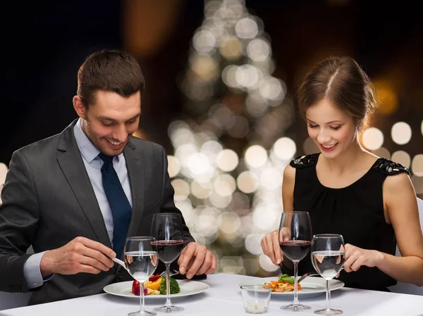 Smiling couple eating at christmas restaurant — Stock Photo, Image