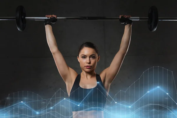 Mujer joven flexionando los músculos con barra en el gimnasio —  Fotos de Stock