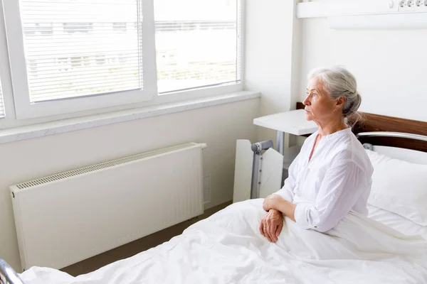 Triste donna anziana seduta sul letto al reparto ospedaliero — Foto Stock