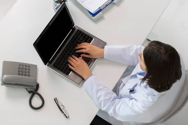 Mujer médico escribiendo en el ordenador portátil en la clínica —  Fotos de Stock