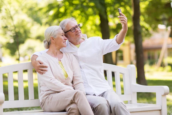 Пожилая пара делает селфи на смартфоне в парке — стоковое фото