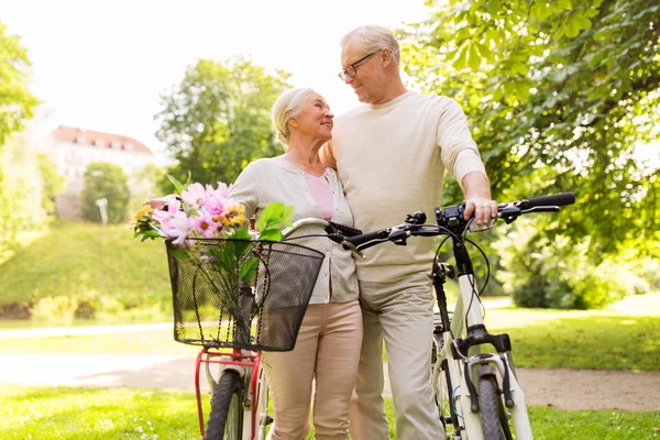 Счастливая пожилая пара с велосипедами в летнем парке — стоковое фото
