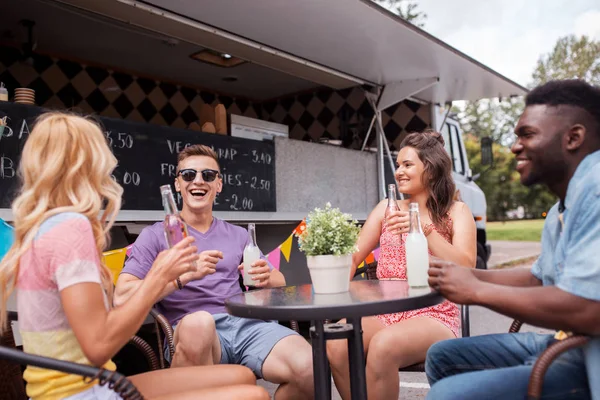 Amici con bevande seduti a tavola al food truck — Foto Stock